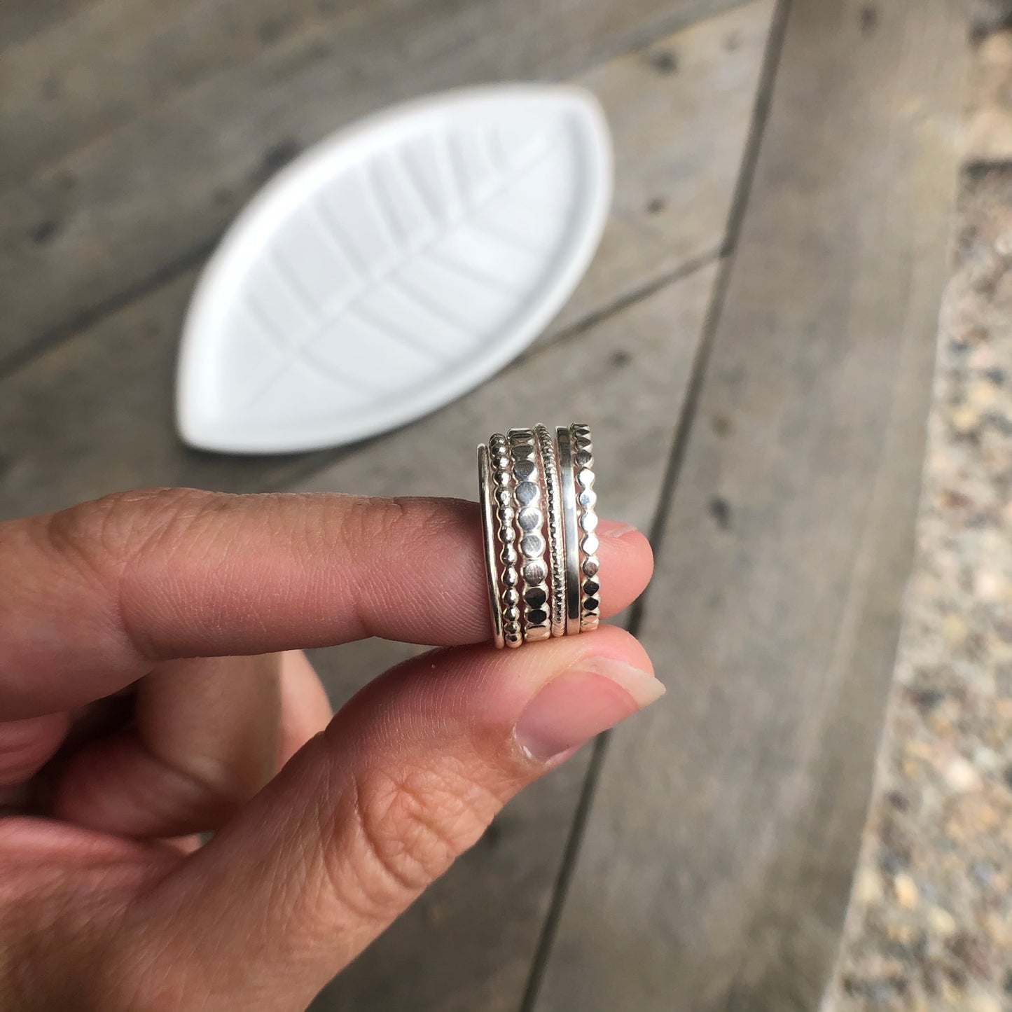 Woman holding several silver stacking rings - Trisha Flanagan