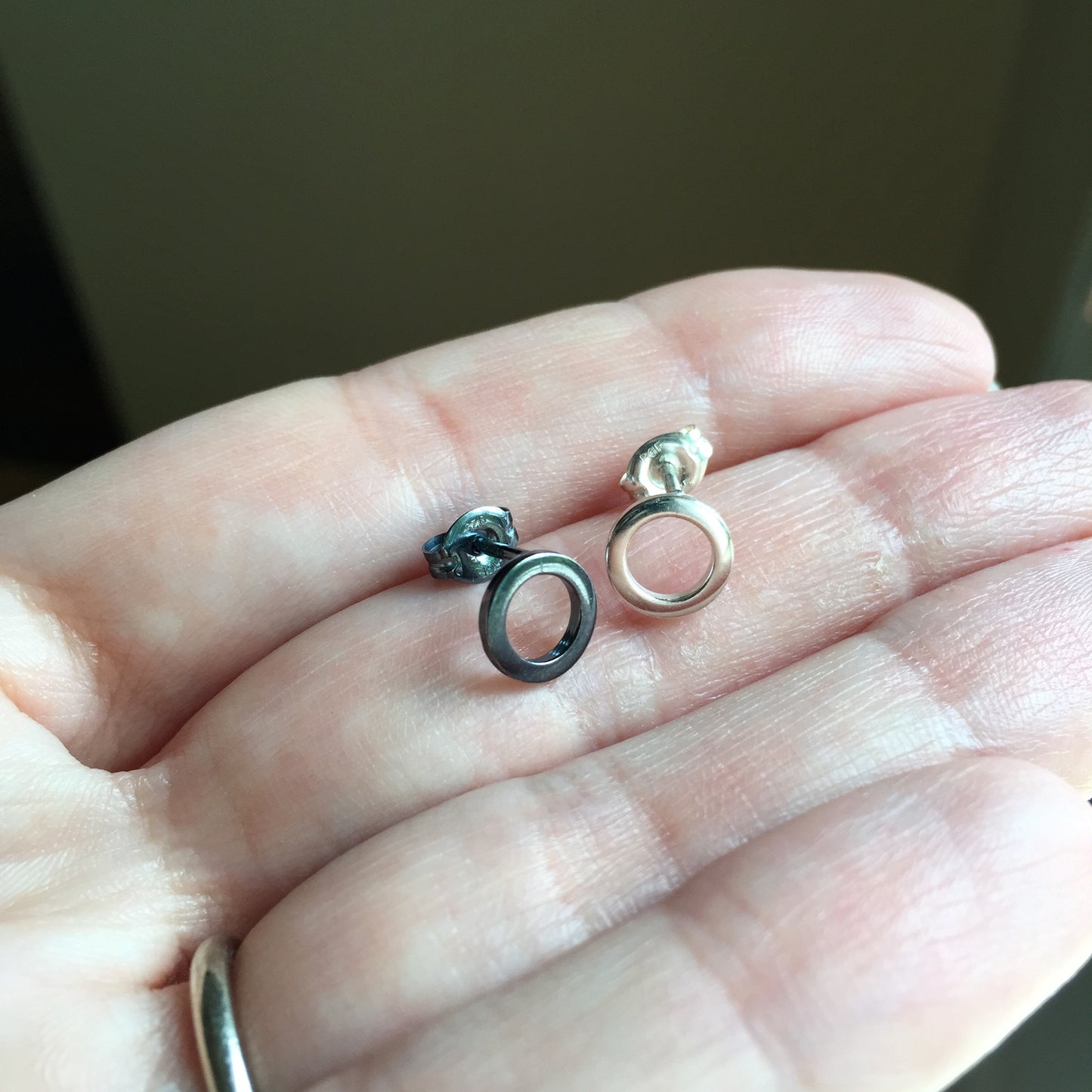 Woman holding One Silver Open Circle Stud Earring and one Black Silver Open Circle Stud Earring - Trisha Flanagan
