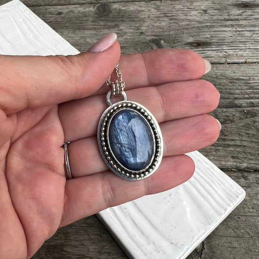 Woman holding up the Kyanite and Deer Statement Pendant front view