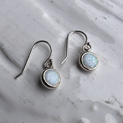 Silver earrings with round gemstones on a marble surface