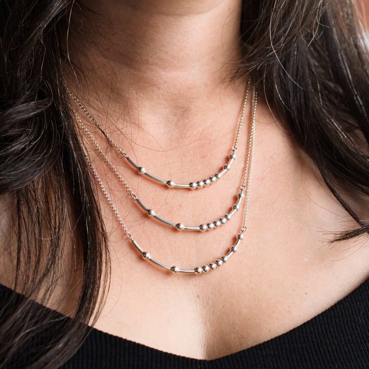 Women wearing a 16, 18 and 20 inch silver necklace to demonstrate different necklace lengths on the body 