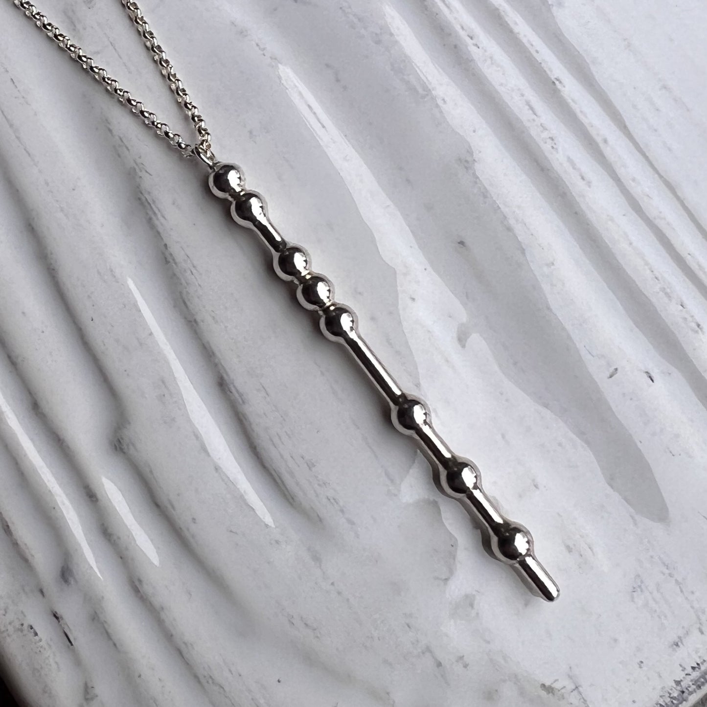 Silver necklace with a unique design on a marble surface