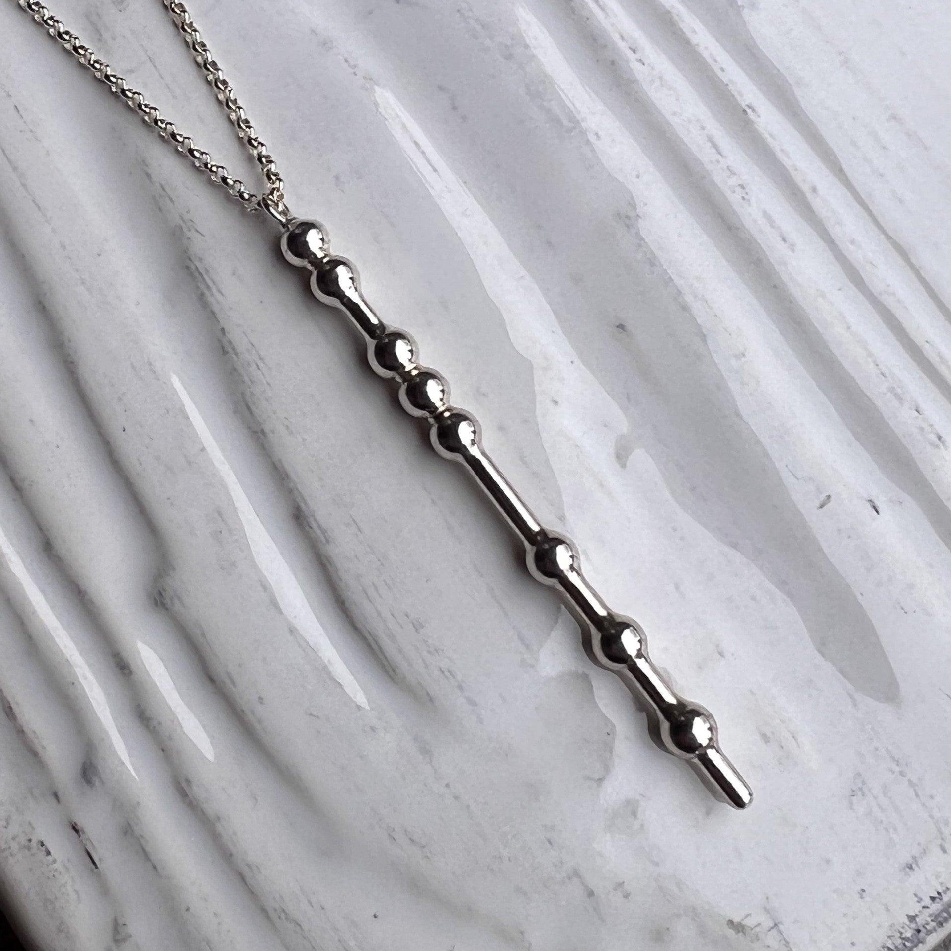 Silver necklace with a unique design on a marble surface