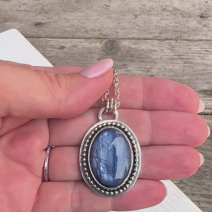 Woman handling the Kyanite and Deer Statement Pendant showing both sides.