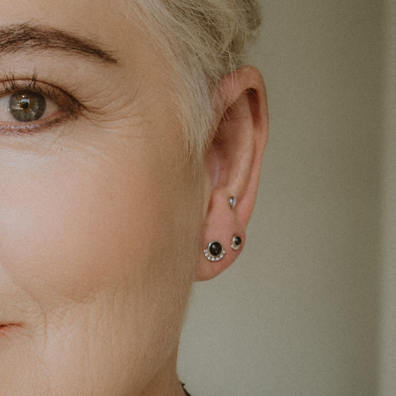 Woman wearing different size gemstone eyelash stud earrings - Trisha Flanagan
