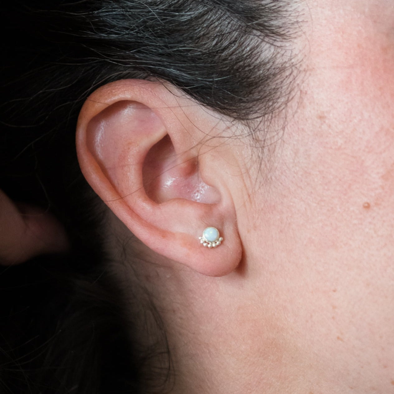 Woman wearing a gemstone stud earring close up - Trisha Flanagan 