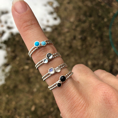 Woman wearing different size gemstone stacking rings - Trisha Flanagan