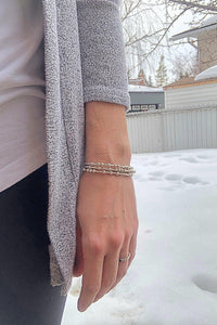Woman wearing three silver Morse Code Bracelets in the winter