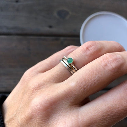 Woman wearing an Emerald Ring and two silver band rings - Trisha Flanagan
